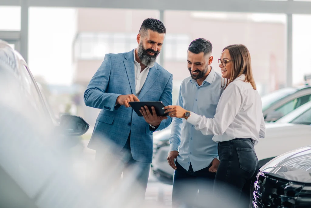 Un concessionnaire vend une voiture à un jeune couple.