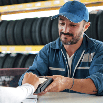 Une femme paie via un TPE dans un garage automobile.